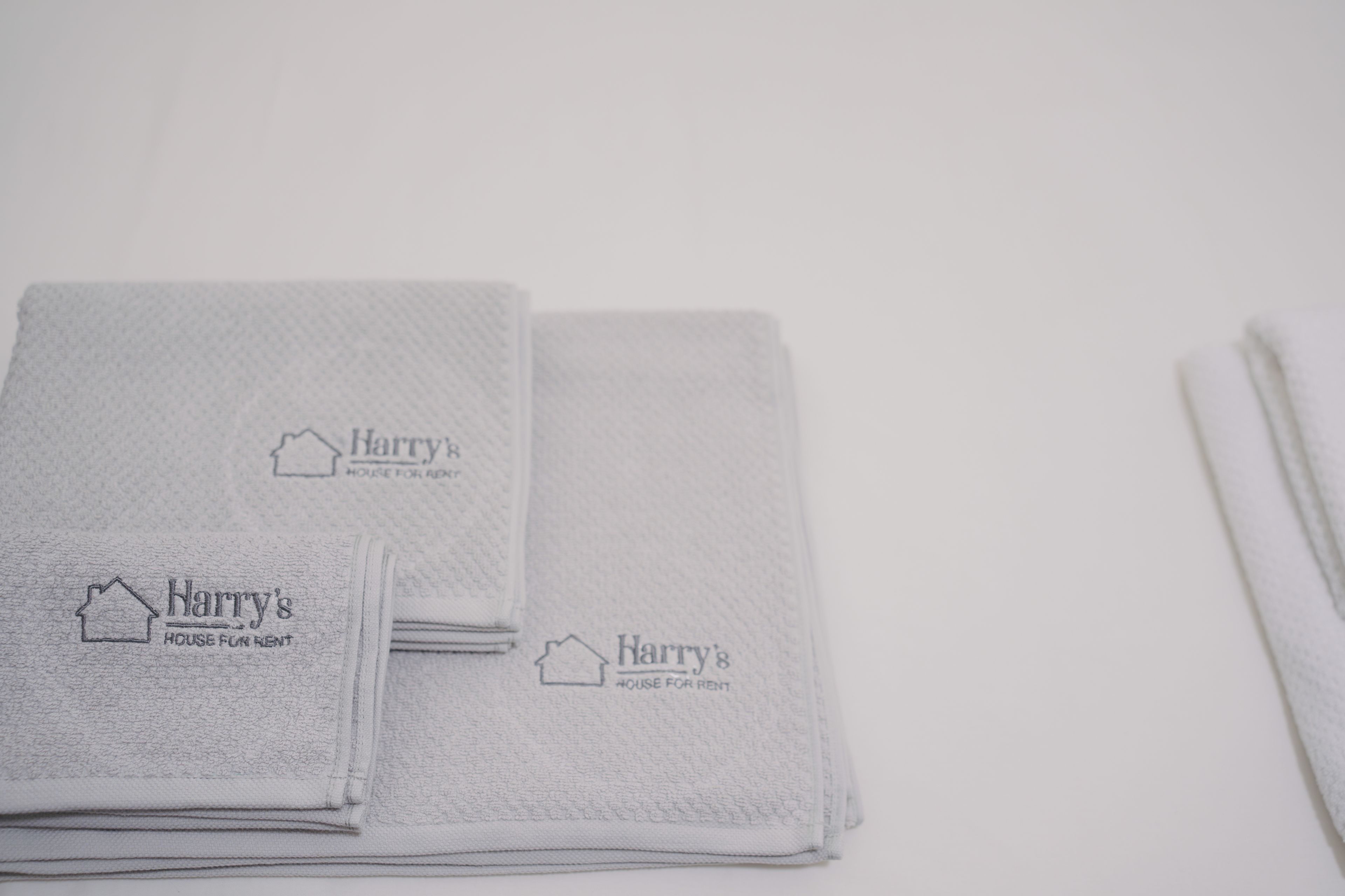 Des serviettes pliées avec soin, portant l’inscription « Harry’s House for Rent », indiquant qu’il s’agit d’un bien immobilier à louer.
