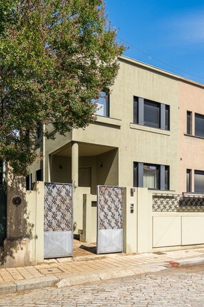 A modern two-story building with a flat facade, a covered entrance, and a gated driveway. - GuestReady - PoetikBlue - Room 5 (Porto)