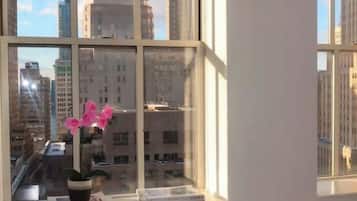 A room with a large window, a glass table, and a chair.