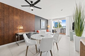 A modern living room with a dining area, a ceiling fan, and a view of the cityscape. - Luxury Condo Steps from Fort Lauderdale Beach (Fort Lauderdale)