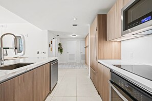 Una cucina moderna con mobili in legno, un lavello in acciaio inossidabile e un forno a microonde integrato.