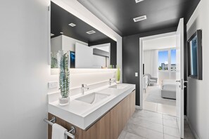 Un bagno moderno con un mobile lavabo doppio, uno specchio grande e vista sull'area soggiorno.