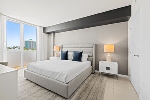 Una camera da letto moderna con un letto grande, lampade sui comodini e vista sulla città.