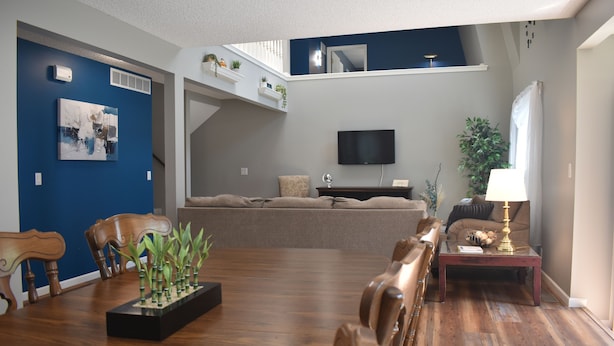 Een woonkamer met houten vloer, een bank, een televisie en een salontafel.