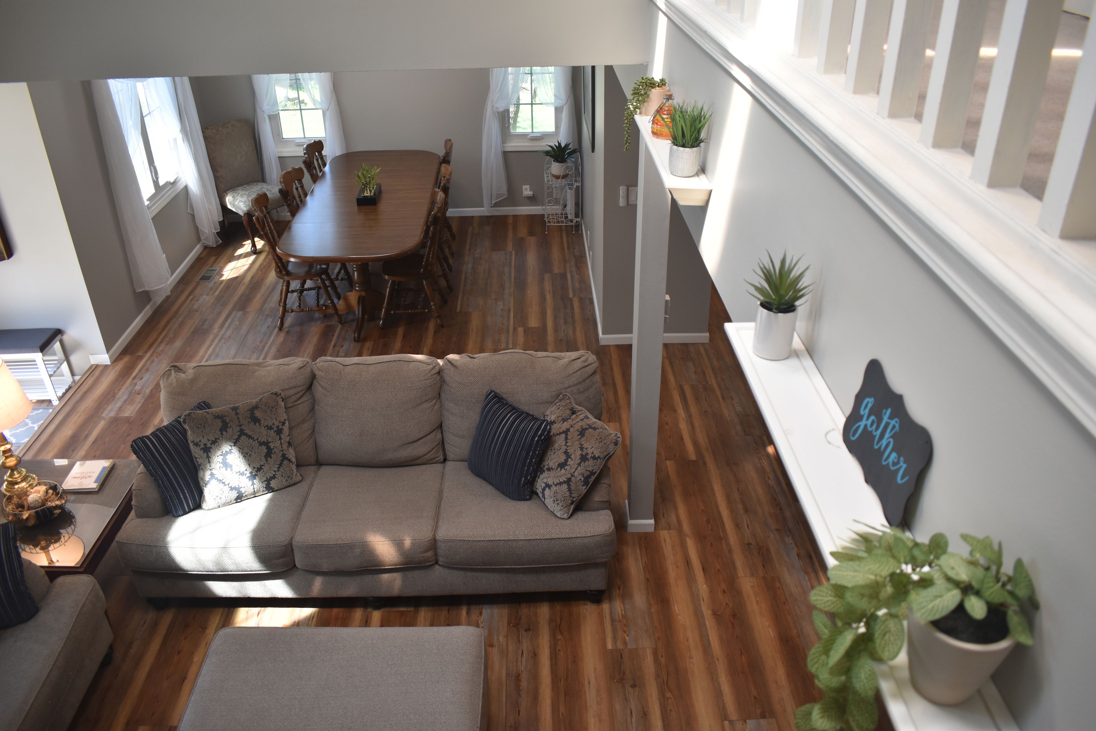 Un vaste espace de vie doté d’un plancher en bois, d’un ensemble de canapés, d’une table à manger avec des chaises et d’un escalier muni d’une rampe.