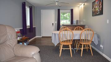 A dining area with a table and chairs, a ceiling fan, and a door leading to another room.