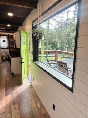 A kitchen with a green door, wooden cabinets, and a window overlooking a deck with outdoor furniture.