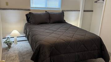 A bedroom with a bed, a window, a lamp, and a walk-in closet.