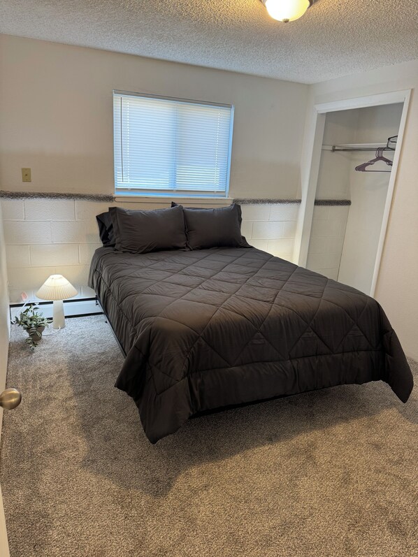 A bedroom with a bed, a window, a lamp, and a walk-in closet.