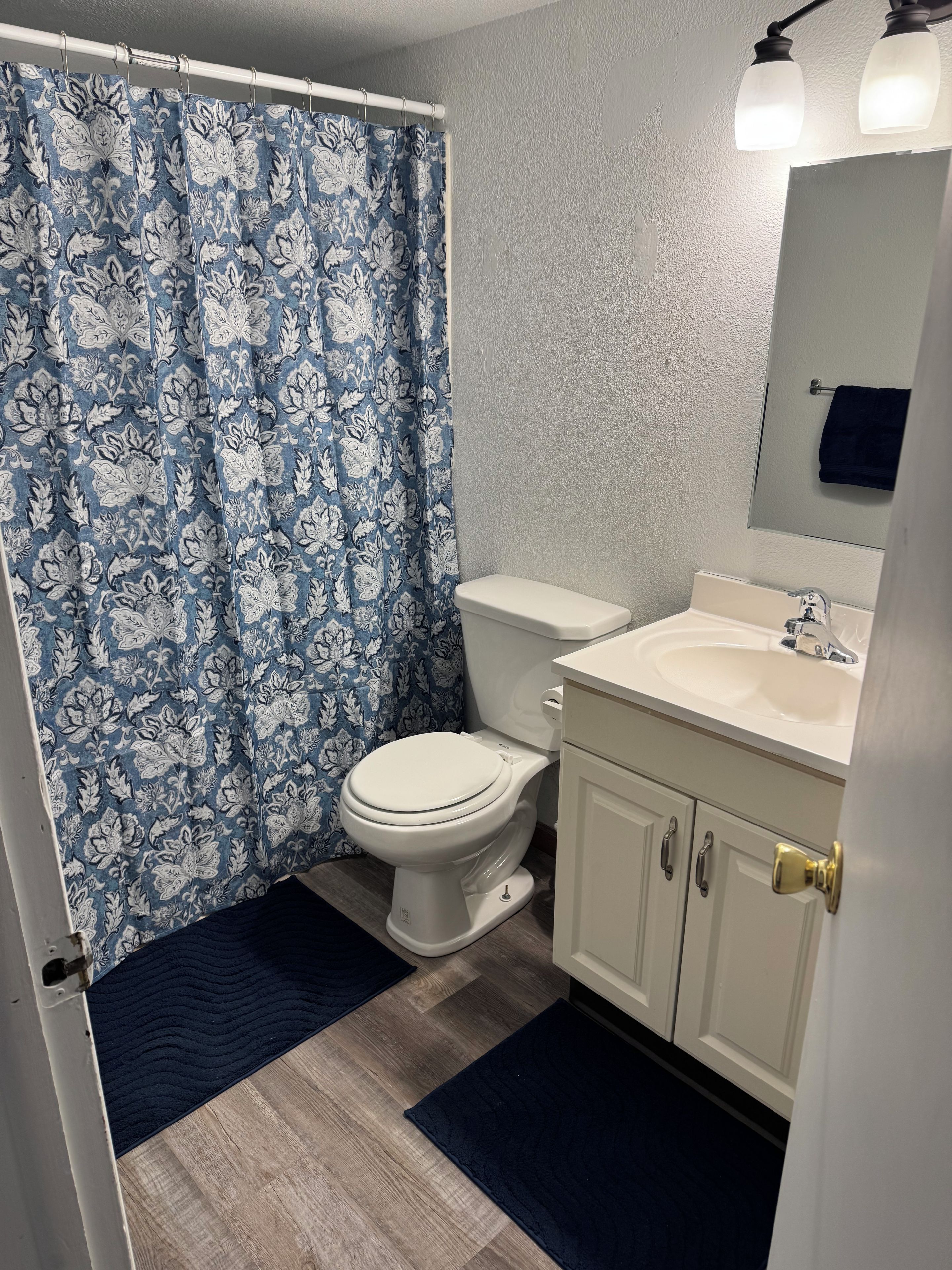 Een badkamer met toilet, wastafel en douchegordijn.