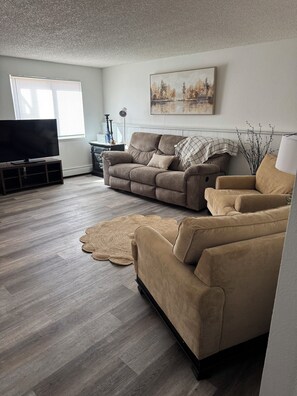 A living room with a flat-screen TV, two sofas, a coffee table, and a fireplace.