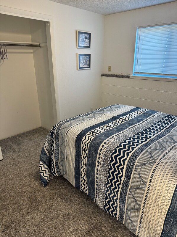 A bedroom with a bed, a closet, and two framed pictures on the wall.