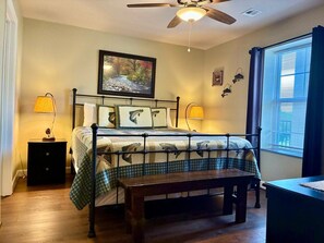 A bedroom with a bed, bedside lamps, a ceiling fan, a window with blinds, and a painting on the wall. - Unit 5402- FREE Attraction Ticket with EACH night Stay Including Dollywood (Pigeon Forge)