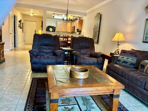 A living room with a coffee table, two leather sofas, a rug, and a dining area in the background. - Unit 5402- FREE Attraction Ticket with EACH night Stay Including Dollywood (Pigeon Forge)