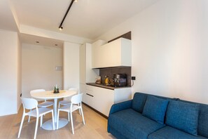 A compact living space with a kitchenette, a dining area with a round table and chairs, and a sofa. - Stella D'Oriente Apartment in Central Bari with Balcony, Wi-Fi, and Air Conditioning (Bari)