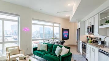 A modern apartment with a green sofa, a dining area, and a kitchen.