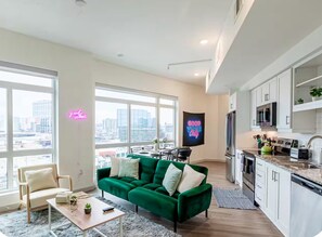 Ein modernes Apartment mit einem grünen Sofa, einem Essbereich und einer Küche.