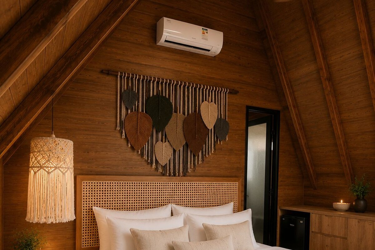 Un dormitorio con cama, mesita de noche, aire acondicionado instalado en la pared, un adorno en la pared y ventilador de techo.
