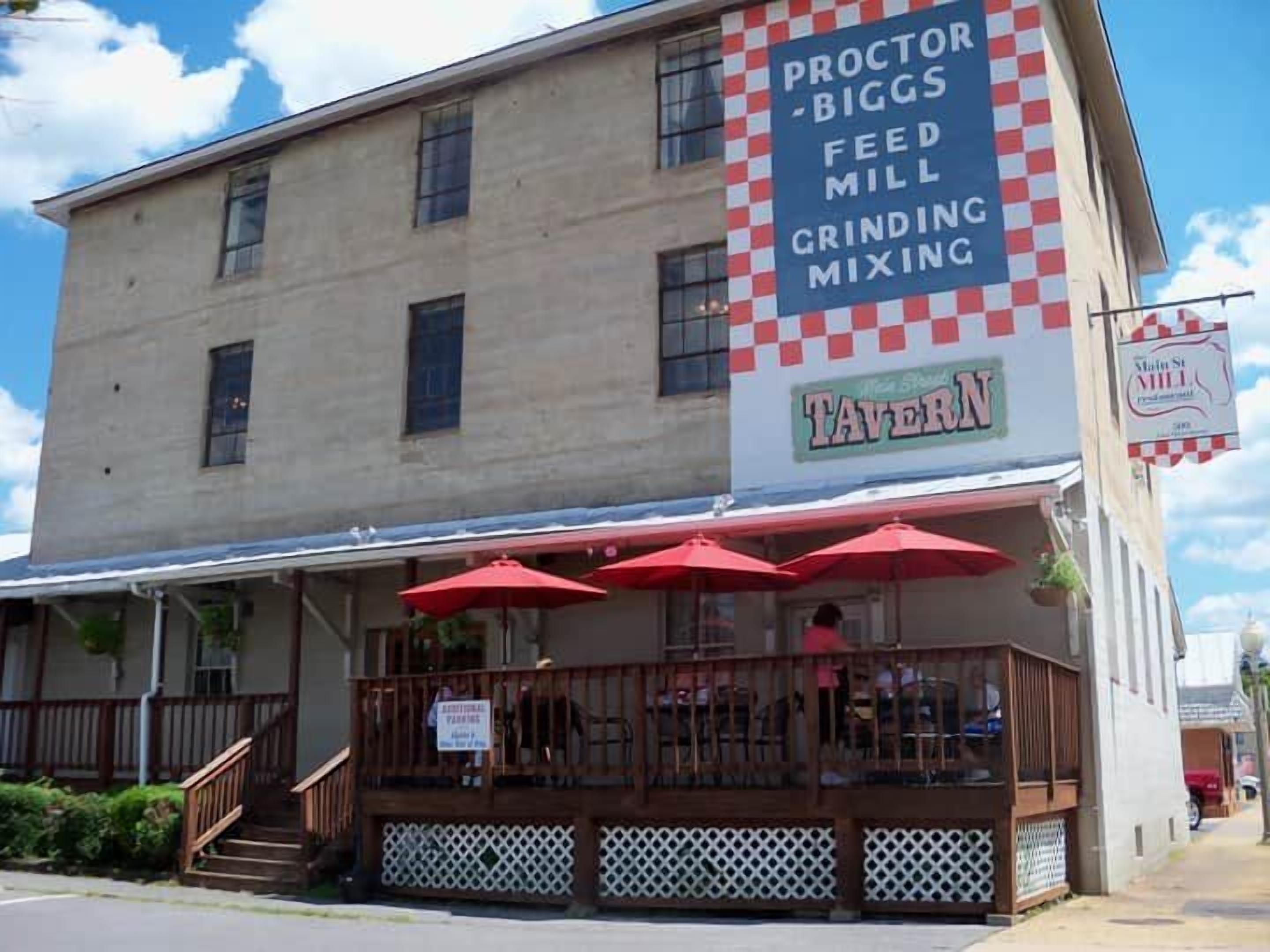 A building with a sign for 'Proctor Biggs Feed Mill Grinding' and a 'Tavern' sign.