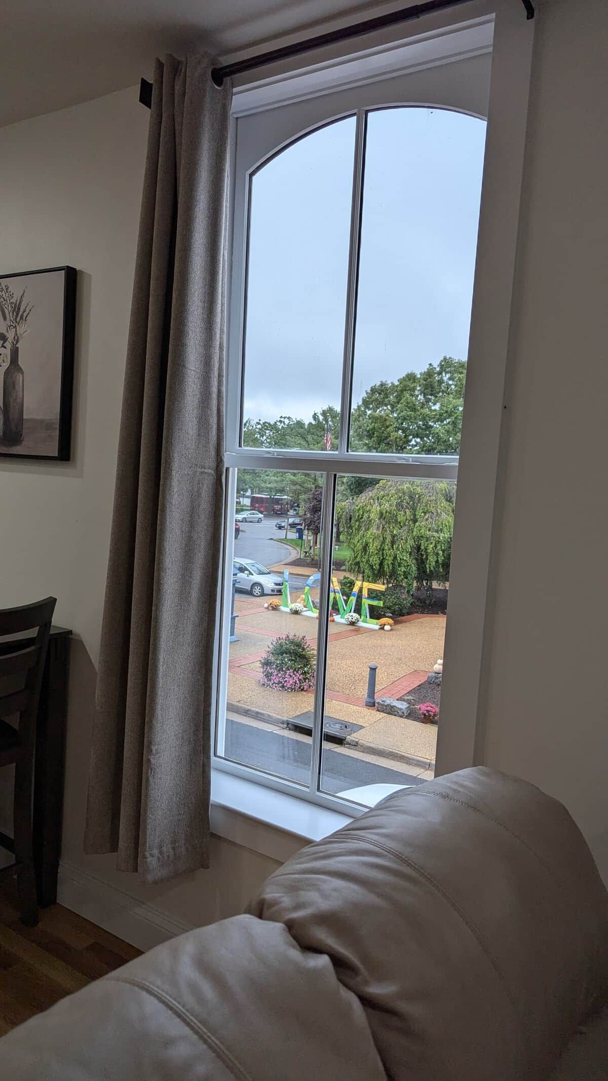 A room with a large window, a chair, a table, and a sofa.