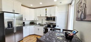 Una cocina moderna con armarios blancos, electrodomésticos de acero inoxidable y encimera de mármol.