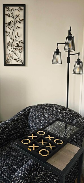 A room with a patterned sofa, a framed artwork, and a floor lamp.