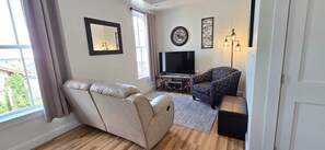 A living room with a reclining chair, a sofa, a television, and a decorative wall piece.