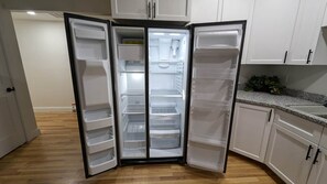 A kitchen with a built-in refrigerator, white cabinets, and a granite countertop.