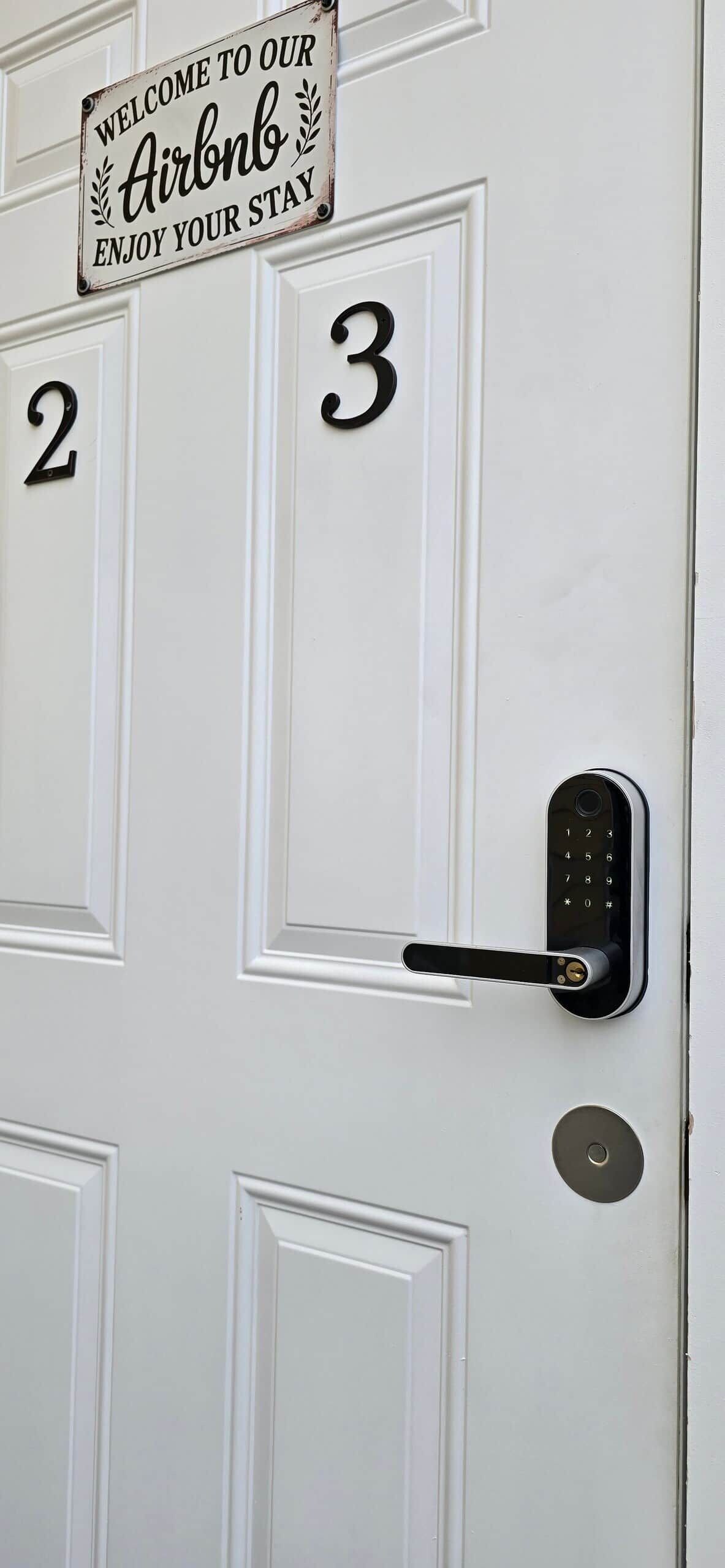 A white door with a sign reading 'Welcome to our Airbnb Enjoy your stay' and the numbers '2' and '3' indicating room numbers.