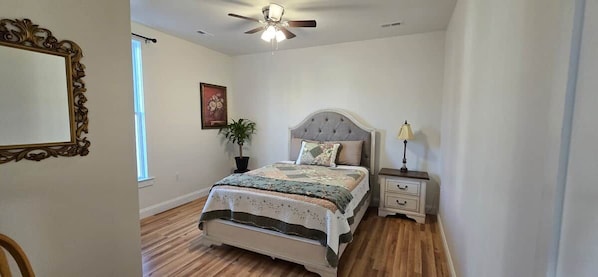 A bedroom with a bed, bedside tables, a ceiling fan, and a window.