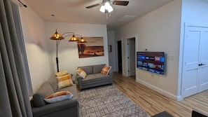 A living room with a sofa, a television, and a floor lamp.