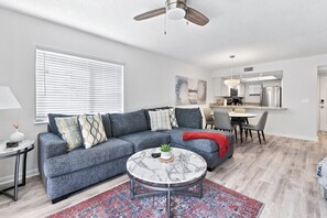 A modern living room with a grey sofa, a marble coffee table, and a red throw blanket. - The Beach Club Retreat (St. Augustine)