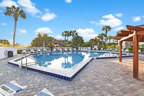 A swimming pool with lounge chairs and a pergola, surrounded by palm trees. - The Beach Club Retreat (St. Augustine)