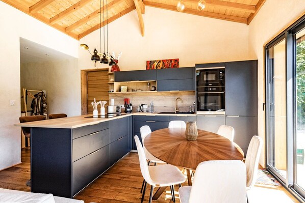 Una cocina moderna con una isla central, un área de comedor con una mesa redonda y un ventanal que proporciona luz natural.