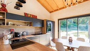 A modern kitchen with a wooden island, built-in appliances, and a dining area with a large window offering a view of the outdoors.