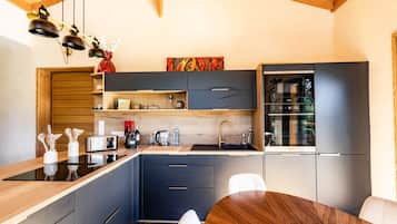 A modern kitchen with a wooden ceiling, built-in appliances, and a dining area with a round table.