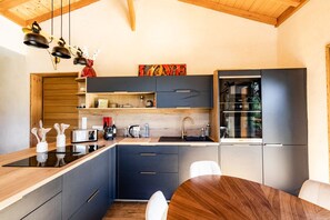 A modern kitchen with a wooden ceiling, built-in appliances, and a dining area with a round table.