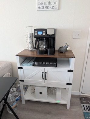 Ein Kaffee-Bereich mit Kaffeemaschine, einer Tasse und einem Schild darüber.