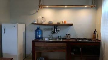 Cocina compacta con refrigerador, lavamanos y encimera de madera.