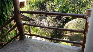 Un espacio al aire libre con suelo de piedra, barandilla de madera y amarres de cuerda.