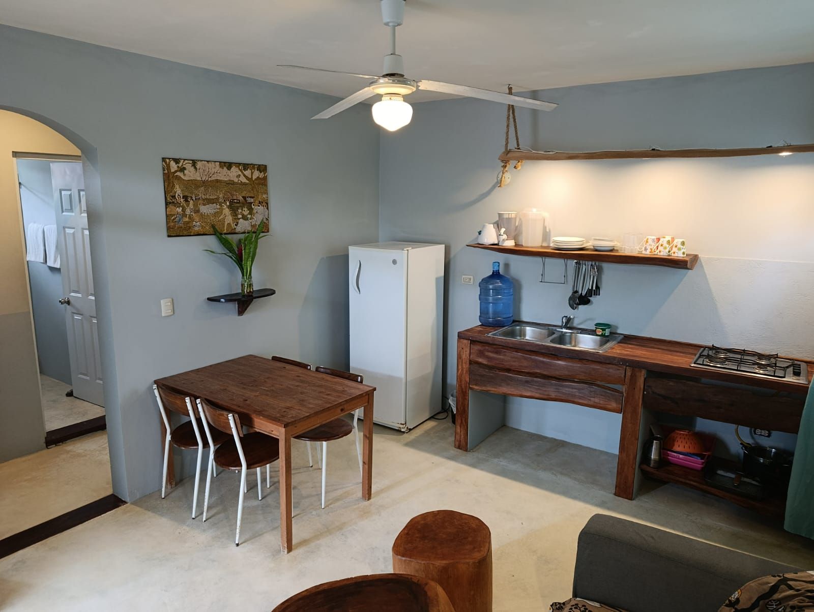 Cocina compacta con una mesa de comedor, sillas, un refrigerador, estufa y ventilador de techo.