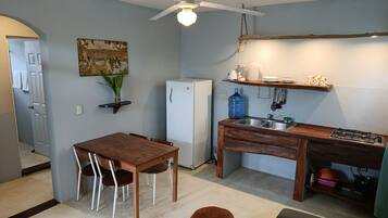 Cocina compacta con una mesa de comedor, sillas, un refrigerador, estufa y ventilador de techo.