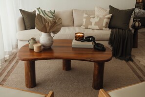 Ein Couchtisch aus Holz mit einer Vase, einer Kerze und einem Buch in einem Wohnzimmer.