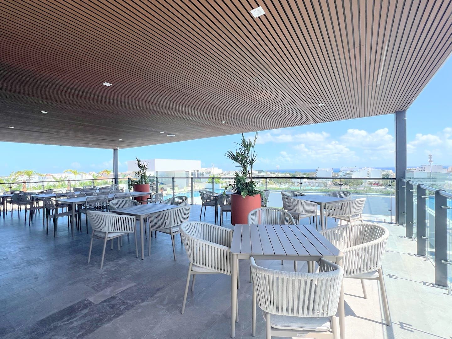 Een terras met tafels en stoelen, een houten plafond en uitzicht op de stadsplattegrond.