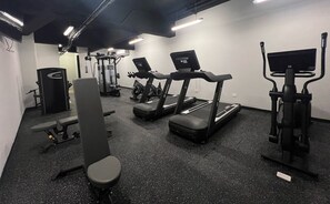 Ein Fitnessstudio mit Laufbändern, einer Bank und Gewichtsmaschinen.