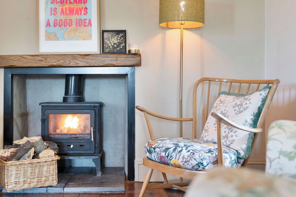 A cozy room with a wood-burning stove, a wicker basket, and a floral-patterned chair.