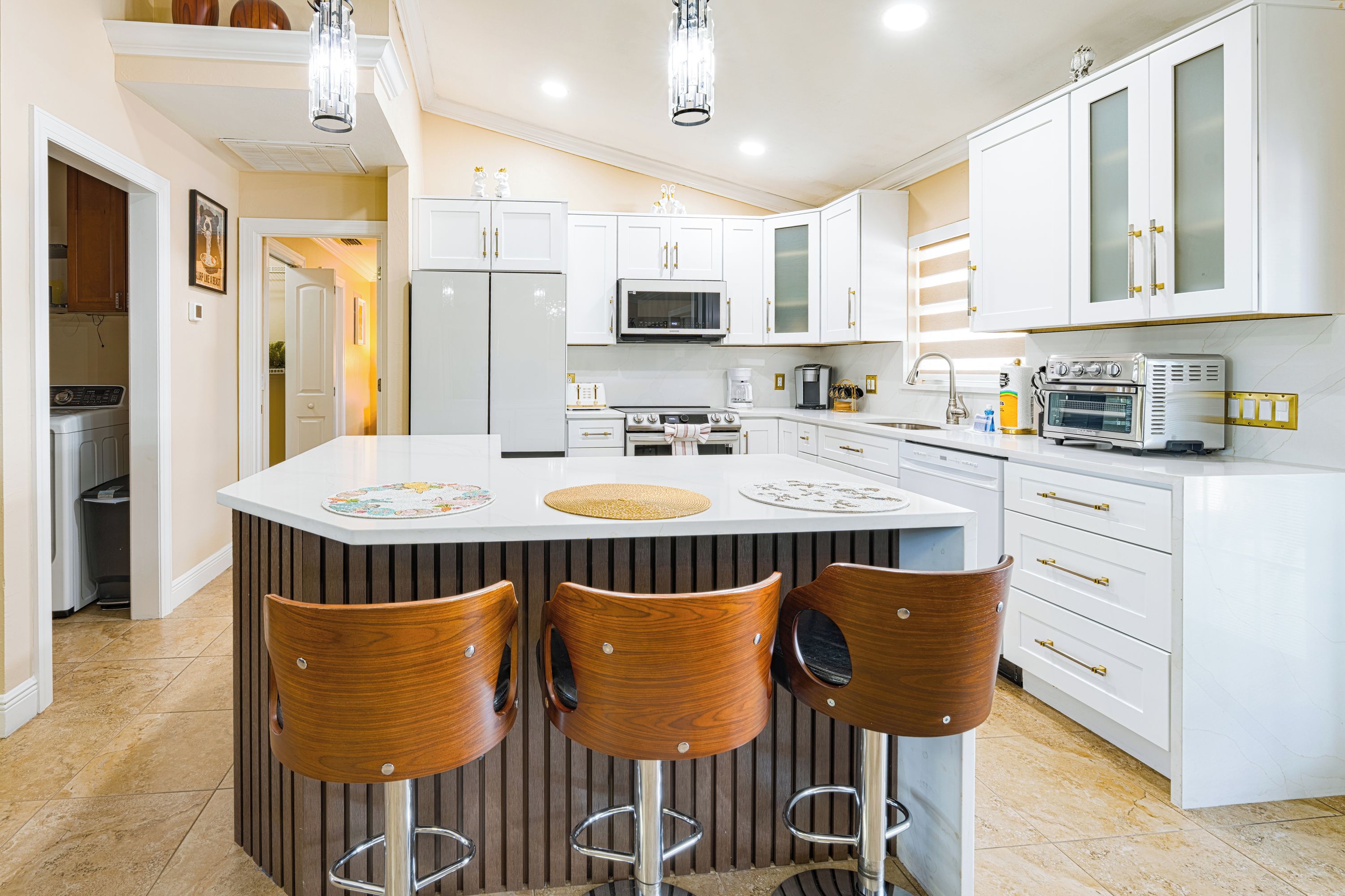 A modern kitchen with a central island, bar stools, and various appliances.