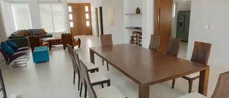 A modern dining area with a large wooden table and chairs, a sofa, and a coffee table.
