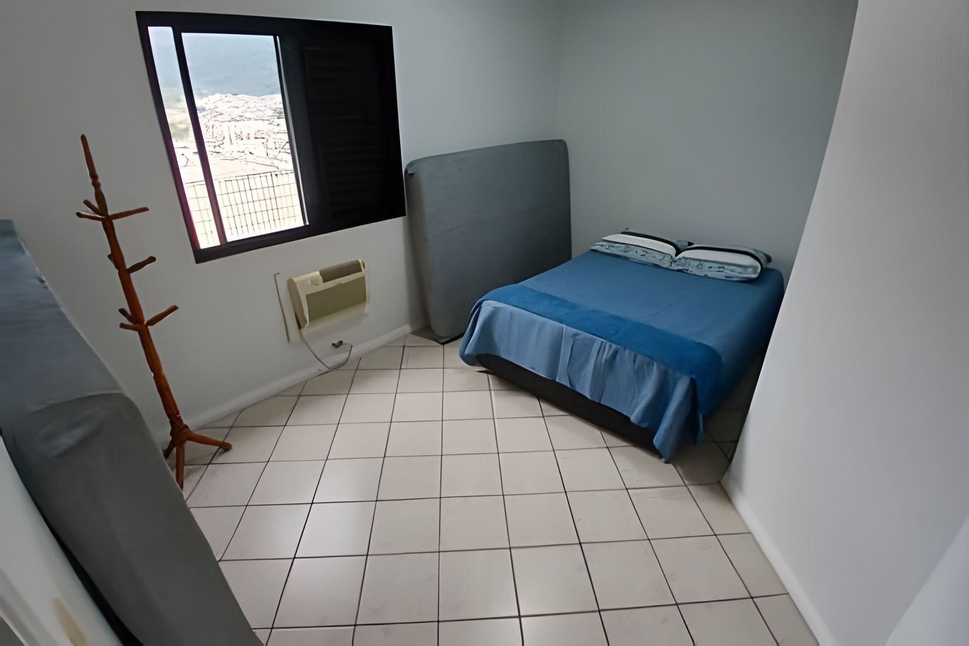 Una habitación pequeña y poco amueblada con cama, ventana y radiador.