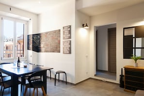 Une cuisine moderne avec une table à manger, des chaises, un petit tabouret et une plante en pot.